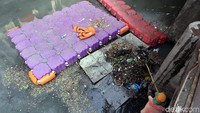 Sampah waduk diangkat ke permukaan menggunakan alat penyaring sederhana.