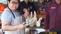 Posenya lucu sambil memegang capitan ketika memasak. Tampilannya lengkap dengan celemek berwarma coklat. Foto: Istimewa