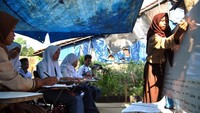 Sejumlah siswa SMP Terbuka belajar di halaman rumah warga. Meski harus melaksanakan kegiatan belajar mengajar dengan kondisi terbatas dan seadanya, para siswa tetap antusias untuk datang dan belajar.
