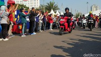 Luhut satmori mengendarai motor listrik Gesits berwarna merah.