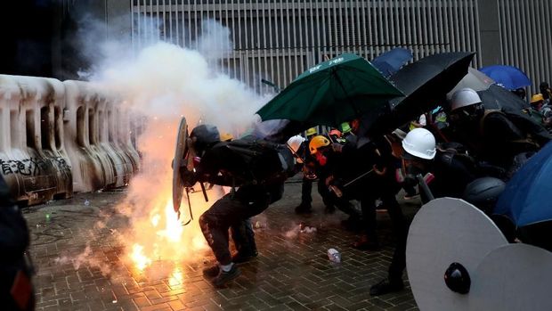 Demonstran Hong Kong berlindung di bawah payung saat gas air mata ditembakkan polisi