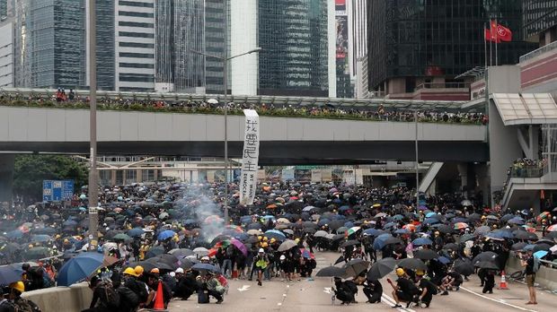 Demonstran Hong Kong berlindung di bawah payung saat gas air mata ditembakkan polisi