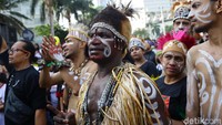 Di lokasi, tampak masyarakat Papua mengenakan hiasan kepala warna warni dan mengenakan kaos bertulisan Papua Adalah Indonesia dan bergambar burung cenderawasih di bagian punggungnya. 