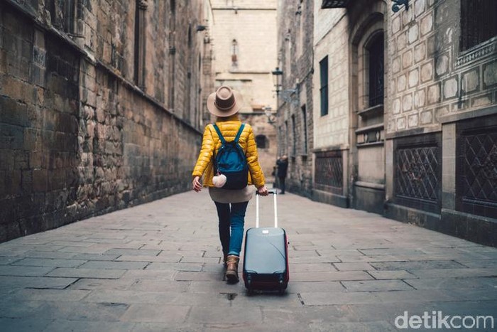 Young woman with suitcase walking at the street in Barcelona