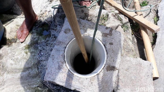 Wardi saat menimba air di sumur bor dengan toples plastik di RT 6 Dusun Batur Turu, Desa Mertelu, Kecamatan Gedangsari, Kabupaten Gunungkidul.
