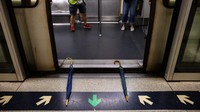 Beberapa demonstran lainnya tampak meletakkan dua payung di tengah-tengah pintu kereta bawah tanah. Aksi para demonstran ini memicu penundaan besar-besaran pada sistem layanan kereta bawah tanah di Hong Kong. Foto: Philip FONG/AFP