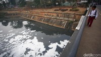 Seorang anak sekolah nampak mengamati busa yang terlihat di saluran Kanal Banjir Timur, Jakarta.