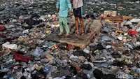 Dua orang anak bermain di atas hamparan sampah.
