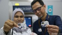 Petugas MRT dan penumpang memperlihatkan pin di depan awak media.