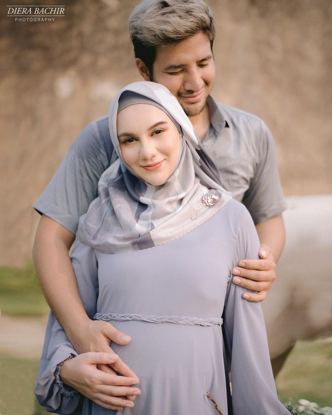 Irish Bella dan Ammar Zoni kompak memakai busana serba abu-abu di pemotretan kehamilan. Irish Bella yang tampil beda dengan hijab mengenakan busana rancangan Evelin Gunawijaya. Sedangkan Ammar Zoni dibalut kemeja dari Wong Hang Tailor. Foto: instagram @dierabachir
