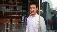 Muzni Zakaria berjalan meninggalkan gedung KPK sambil melempar senyuman.