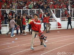 Sejumlah suporter turun ke lintasan atletik yang mengelilingi lapangan.