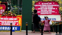 Seorang warga bersama buah hatinya tampak melintas diantara deretan karangan bunga yang menyuarakan pengesahan RUU PKS.