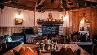 Interior dalamnya dibuat dari kayu dengan gaya rumah jadul yang nyaman. Ada sofa yang menghadap langsung kke perapian (The Groundskeepers Cottage) 