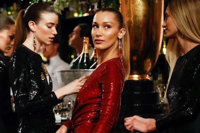 Gaya Bella Hadid kian sempurna dengan padanan statement earrings yang dihiasi batu permata merah. Tidak ketinggalan rambut bergaya pony-tail yang sleek. (Foto: Getty Images)