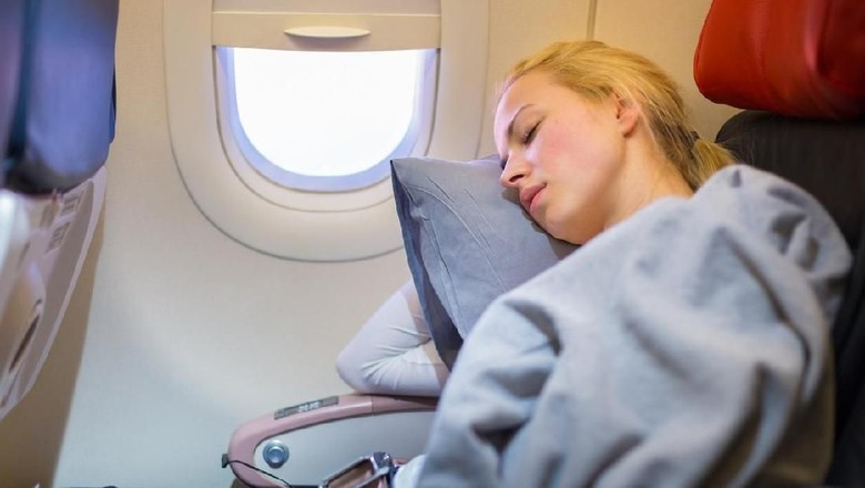 Female passenger sleeping covered with blanket. Comfortable flying.