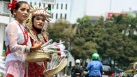 Massa yang mengatasnamakan Masyarakat Penegak Demokrasi (MPD) membagikan bunga dengan memakai pakaian adat.