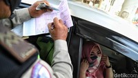 Seorang pengendara yang melanggar ganjil genap menutupi wajahnya saat ditilang polisi.