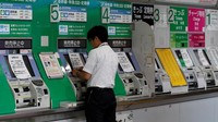 Seorang petugas memasang kertas pemberitahuan terkait penghentian operasi kereta untuk sementara waktu imbas Badai Faxai yang menghantam wilayah Tokyo, Jepang. Issei Kato/Reuters.