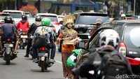 Peserta aksi membagikan bunga di antara lalu lalang kendaraan.