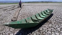 Perahu nelayan dibiarkan teronggok di dasar waduk yang mengering.