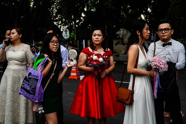 Ada juga beberapa pasangan yang memakai busana merah. Dalam budaya China, merah merupakan simbol keberuntungan dan kebahagiaan. Warna merah juga warna tradisional yang dikenakan pengantin China. Foto: Mohd RASFAN / AFP