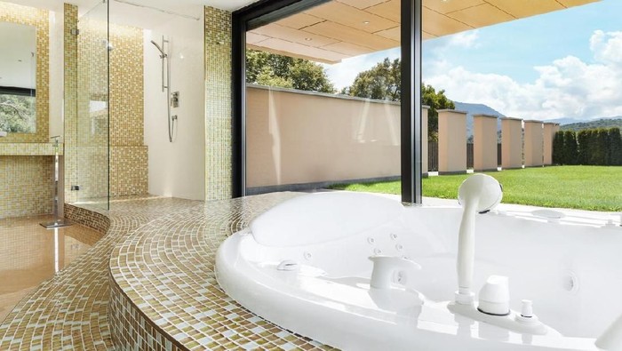 Spacious black bathroom with sparkle floor, big windows, black basin, decorative mirror, violet pouffe and large hot tub