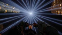 Sejumlah orang mengambil gambar di bawah instalasi lampu dua cahaya kembar Tribute in Light yang dinyalakan untuk memperingati peristiwa serangan 11 September 2001.