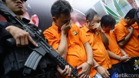 Para tersangka dihadirkan dengan memakai baju tahanan dan tangan diborgol.