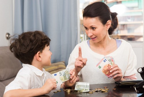 Children and money concept. Woman admonishing teen boy while giving him money at home