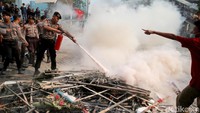 Polisi memadamkan api yang berasal dari aksi bakar karangan bunga sekelompok orang di halaman depan gedung KPK, Jakarta.
