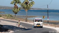 Dengan latar belakang pemandangan pantai, mobil angkutan umum itu melaju dengan sangat lugasnya.