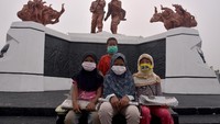Sejumlah anak penjual koran berpose di depan dua patung di Monumen Perjuangan Rakyat Riau dengan masker medis saat kabut asap kebakaran hutan dan lahan (Karhutla) pekat menyelimuti Kota Pekanbaru, Riau, Sabtu (14/9/2019). ANTARA FOTO/FB Anggoro.