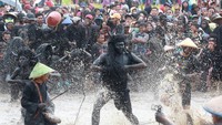 Warga yang berdandan kebo-keboan (kerbau) menceburkan penonton ke dalam kubangan pada ritual adat Kebo-keboan Alasmalang, Banyuwangi, Jawa Timur, Minggu (15/9/2019).