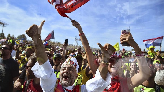 As seen from behind a window, fans of Repsol Honda Team Spanish rider, Marc Marquez celebrate his victory in the San Marino MotoGP Grand Prix race at the Misano World Circuit Marco Simoncelli on September 15, 2019. (Photo by Marco BERTORELLO / AFP)