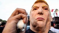 Dari ratusan peserta aksi, salah satunya yaitu Margiata Suharman dari Emancipate Indonesia mengenakan topeng Trump saat melakukan aksi demo di depan gedung DPR RI.