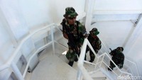 Anggota Marinir TNI AL menaikin anak tanda bangunan menara.