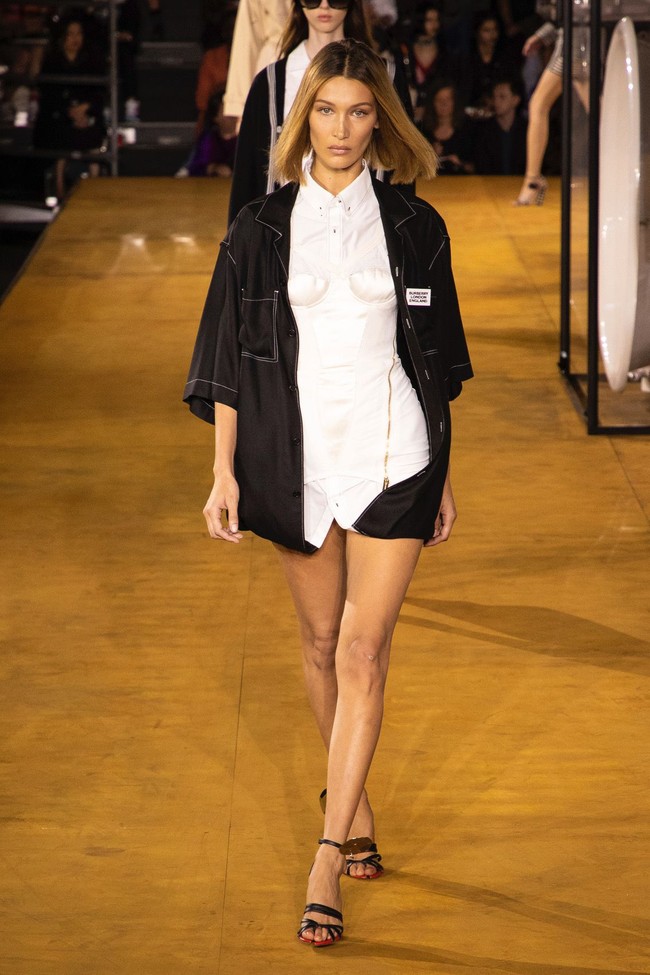 Muncul pula Bella Hadid yang tampak edgy dengan kemeja putih berhiaskan korset serta kemeja hitam sebagai luaran. Tak ada bawahan sehingga mengekspos kaki Bella yang jenjang. (Foto: Vianney Le Caer/Invision/AP)