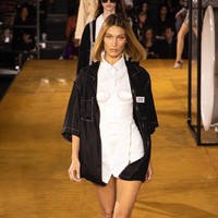 Muncul pula Bella Hadid yang tampak edgy dengan kemeja putih berhiaskan korset serta kemeja hitam sebagai luaran. Tak ada bawahan sehingga mengekspos kaki Bella yang jenjang. (Foto: Vianney Le Caer/Invision/AP)