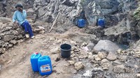 Seorang warga tampak beristirahat sambil menunggu jeriken terisi air. 
