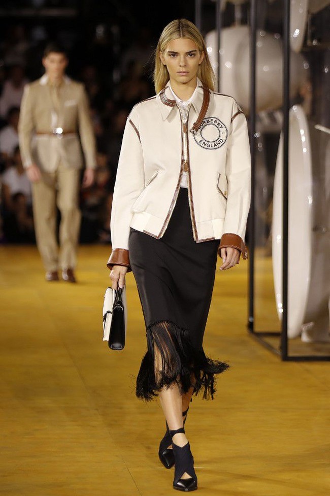 Memeragakan koleksi Burberry Spring-Summer 2020, Kendall Jenner muncul dalam balutan jaket model bomber yang dihiasi detail kulit. Jaket tersebut berpadu apik dengan padanan kemeja dan rok berhiaskan fringe. (Foto: Tolga AKMEN / AFP)