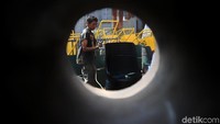 Pekerja mengecat tempat sampah yang terbuat dari tong bekas.