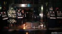 Para peserta aksi juga menyalakan lilin di sekeliling nisan bertuliskan RIP KPK. Suasana di lobby gedung KPK pun dibuat gelap gulita.
