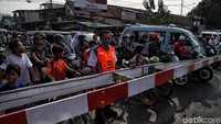 Para pengendara mengantre untuk menunggu kereta api melintas di perlintasan sebidang Bukit Duri Manggarai, Jakarta.