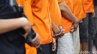 Para tersangka dihadirkan dengan mengenakan baju tahanan dan tangan diborgol.