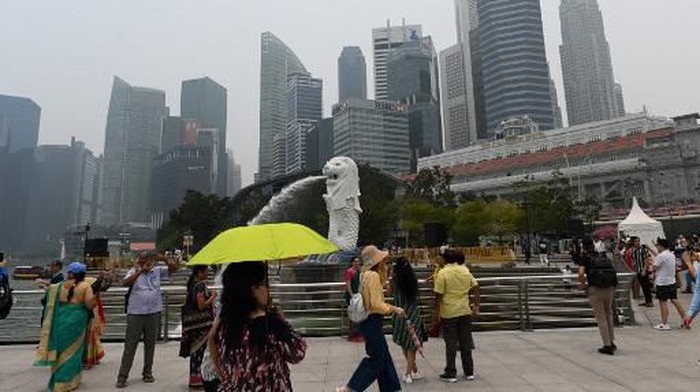 Visitors gather at the landmark Merlion Park as the city skyline is blanketed by haze in Singapore on September 18, 2019. - Air quality worsened in Singapore days before the citys Formula One race, as toxic smog from Indonesian forest fires engulfed the region. (Photo by Roslan RAHMAN / AFP)