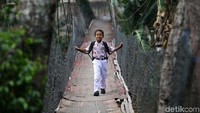 Seorang anak menyeberangi jembatan gantung di perbatasan Kecamatan Cimanggis, Depok dengan Kecamatan Jagakarsa, Jakarta, Kamis (19/9/2019).