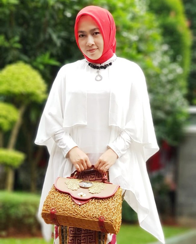 Seperti inilah penampilan Obib Nahrawi saat memamerkan busana rancangannya sendiri. Busana-busananya itu biasanya dia pakai untuk menjalani tugasnya sebagai istri menteri. Seperti outer putih ini dipakainya untuk menghadiri seminar yang digelar Dharmawanita Kemenpora. Saya mengenakan outer yg sengaja sy bikin semi blouse agar bisa di kenakn dlm segala kondisi.. New design dg limited stock...lucu,cantik dan simple, tulisnya pada keterangan foto. Foto: Instagram @obib_nahrawi