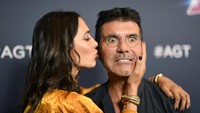 Saat dikecup mesra sang istri, Simon justru menunjukan ekspresi aneh. Frazer Harrison/Getty Images
