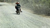 Dua orang warga melintas di jalan yang sedang diperbaiki.
